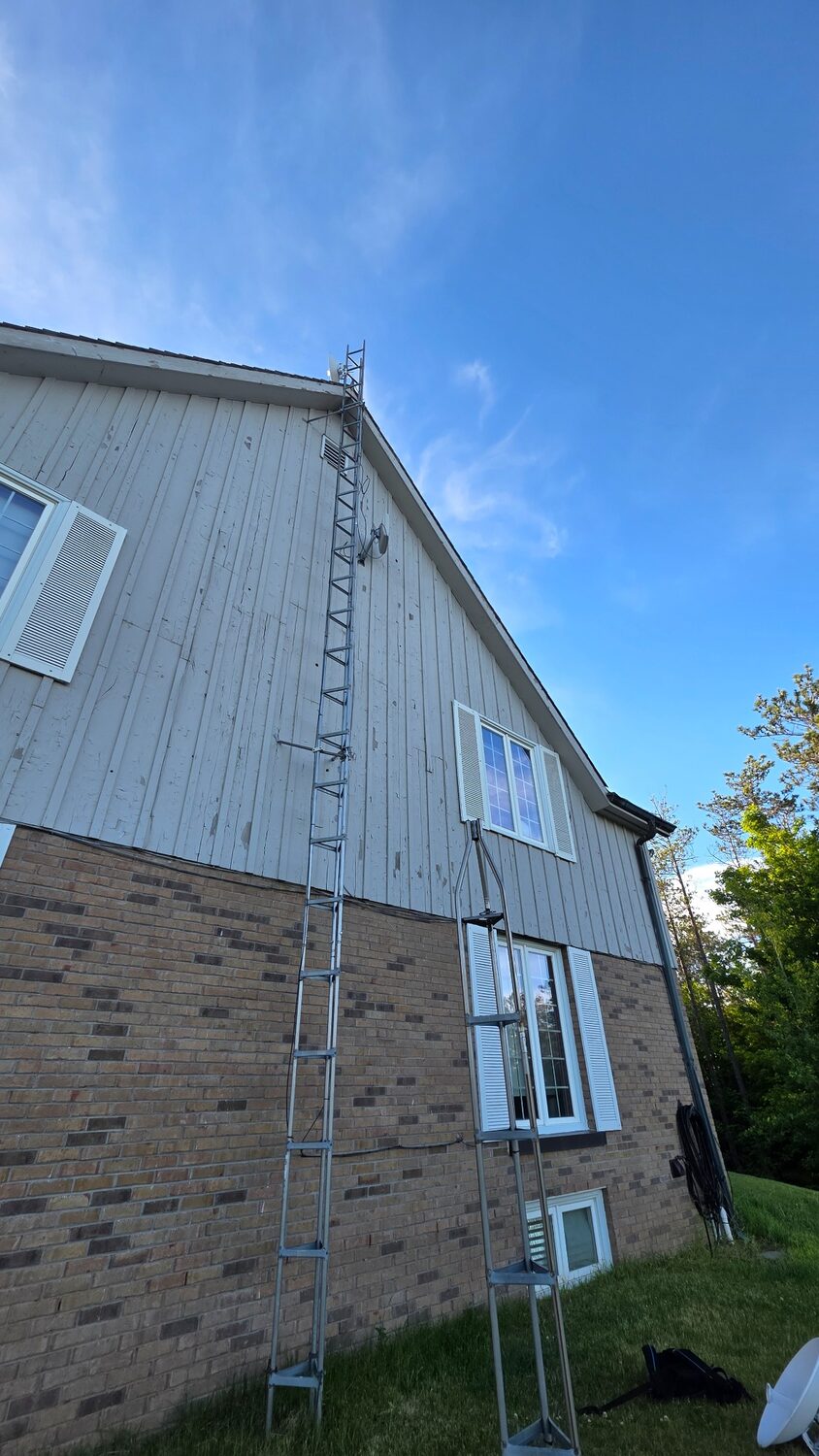 Residential tower partly dismantled beside a house during section-by-section removal.